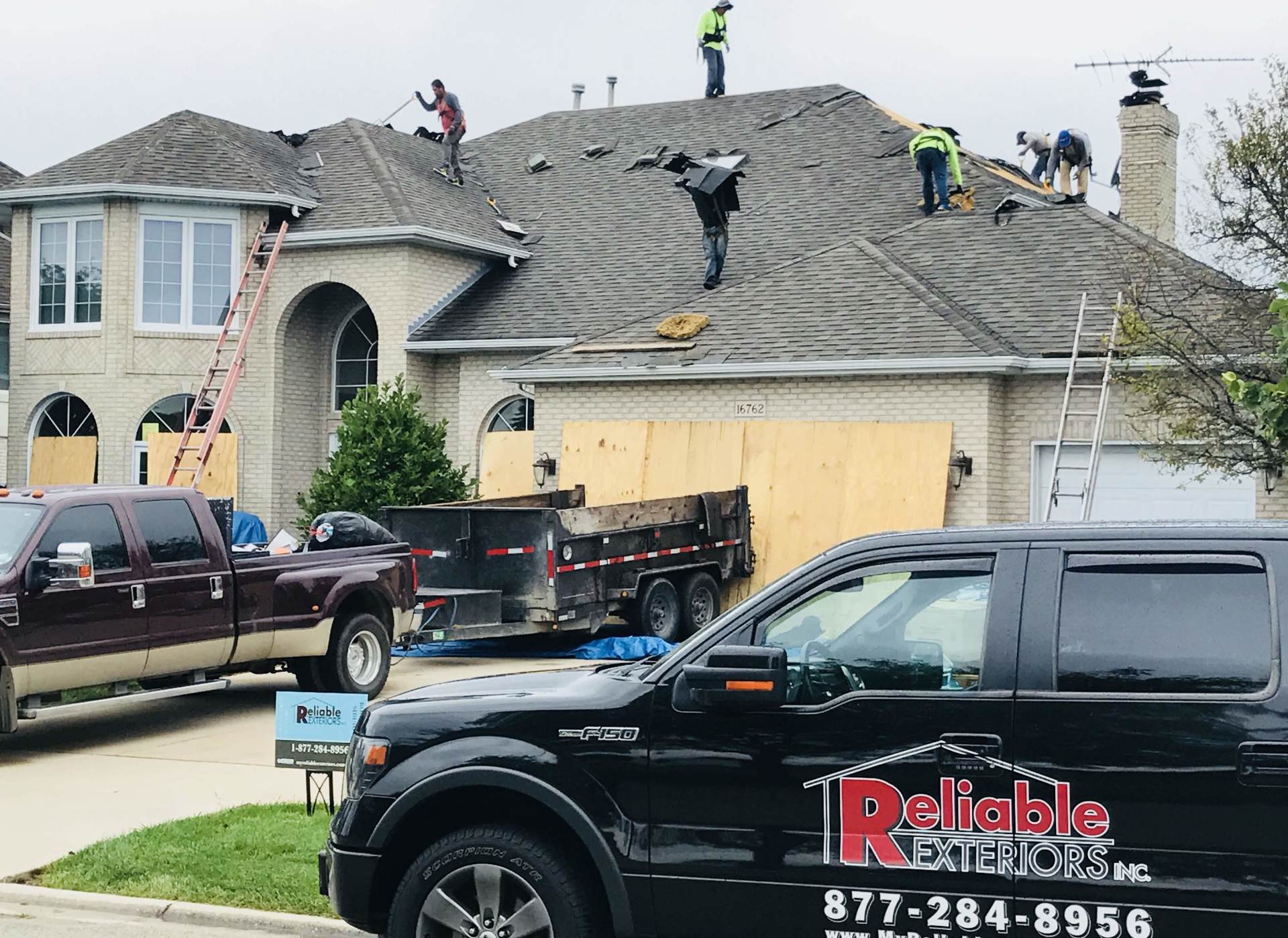 A reliable roofing truck is parked in front of a house