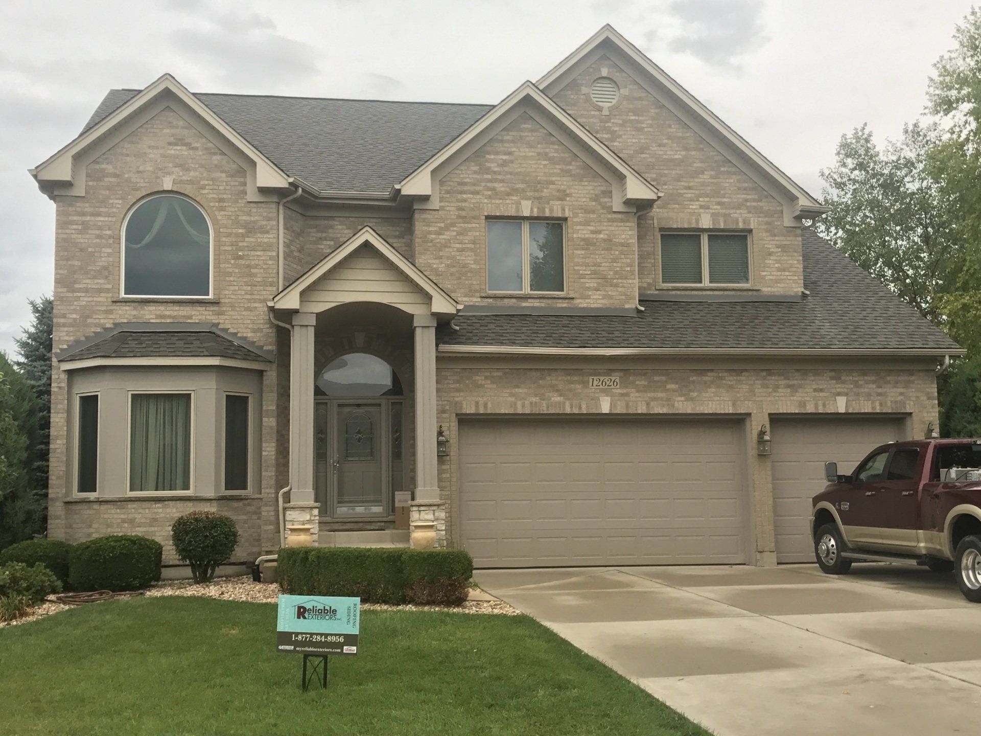 A large brick house with a truck parked in front of it.