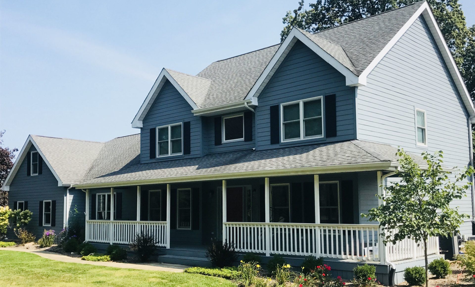 A large blue house with a large porch and a gray roof.