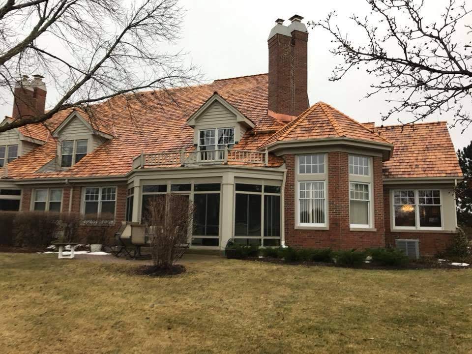 A large brick house with a copper roof and a screened in porch.