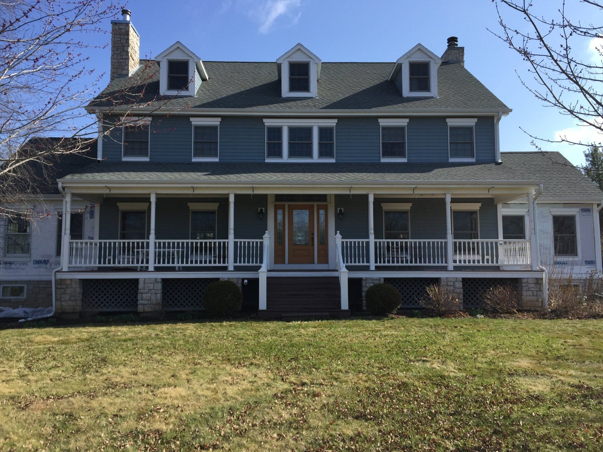 A large house with a large porch and a blue siding