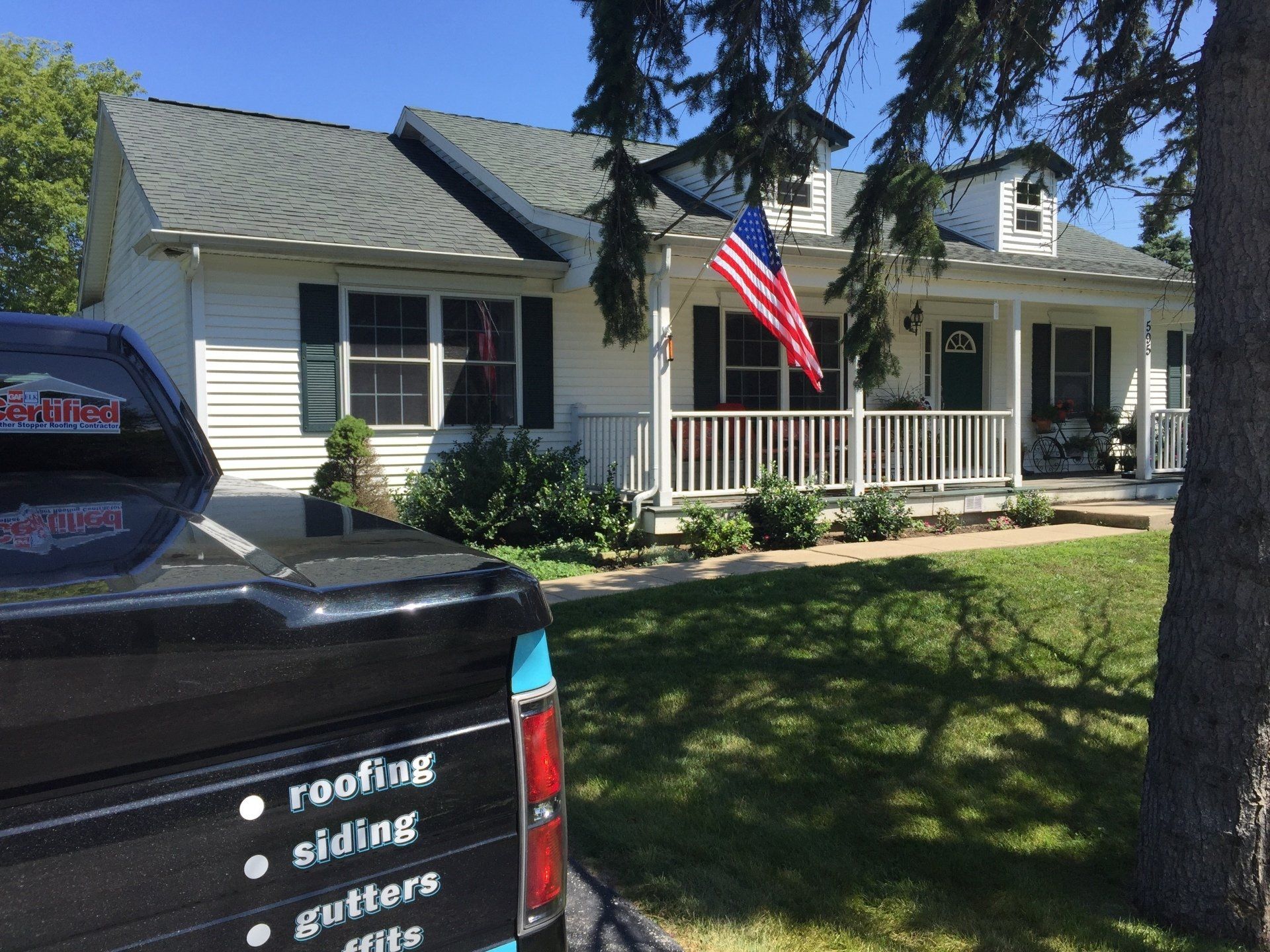A black truck is parked in front of a white house.