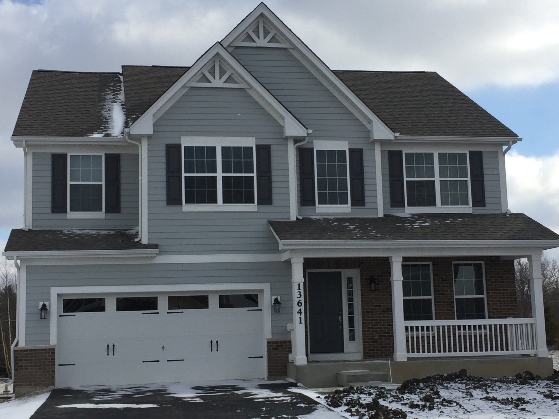 A large house with a white garage door and black shutters