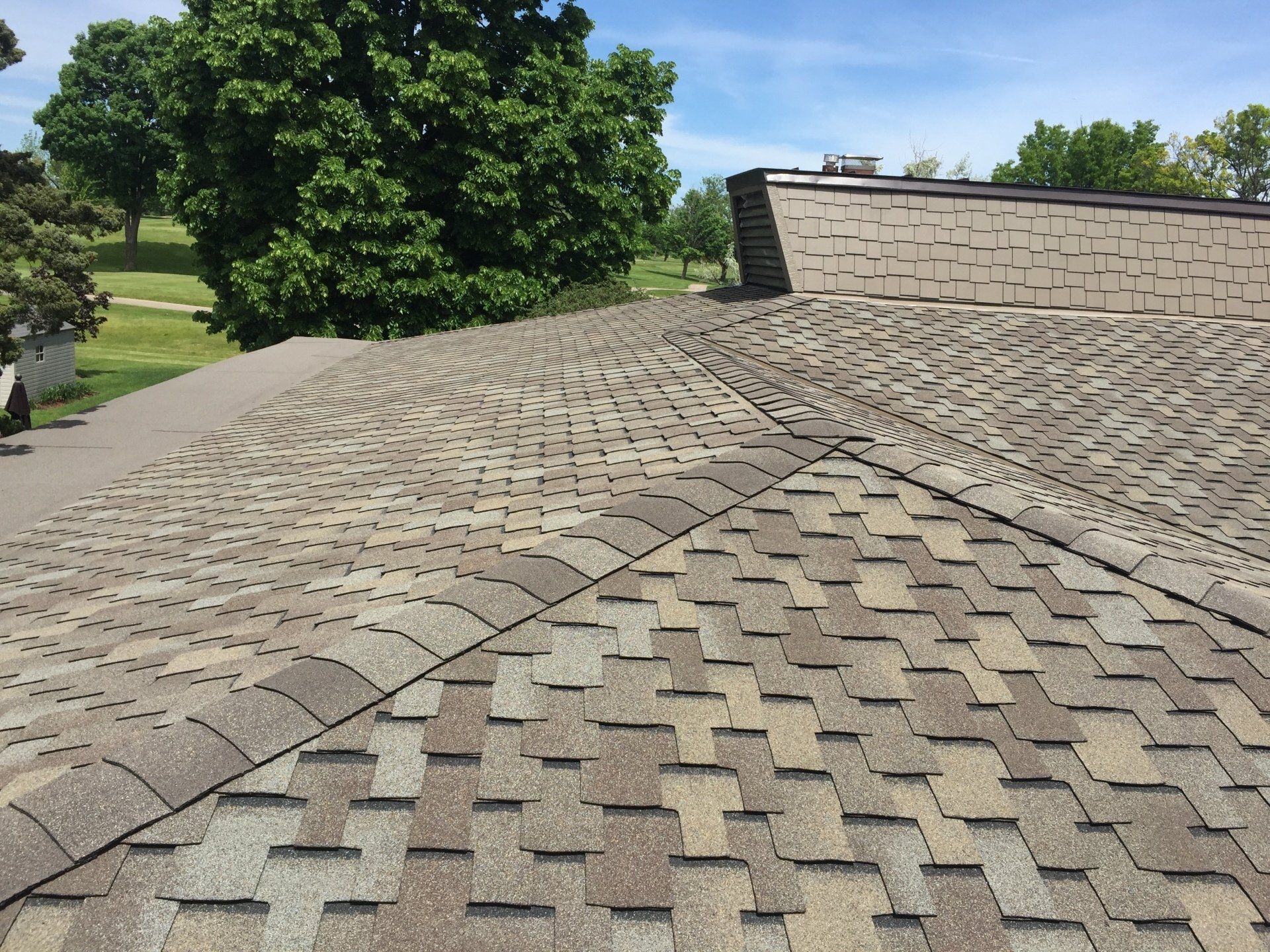 A roof with a lot of shingles on it and trees in the background.
