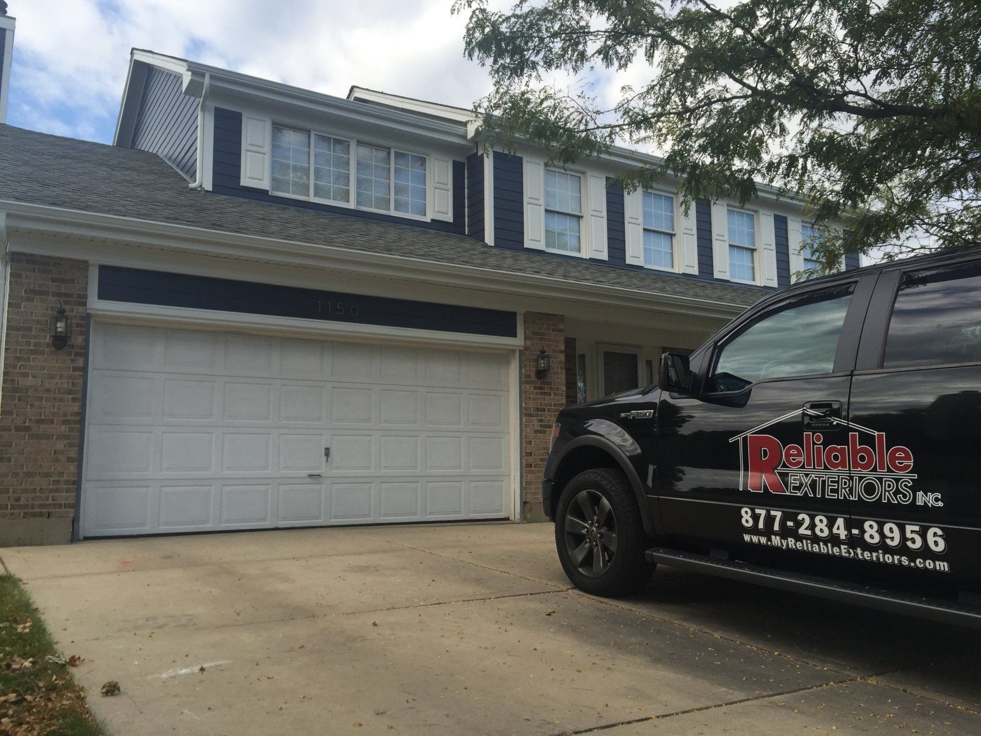 A black truck is parked in front of a house.