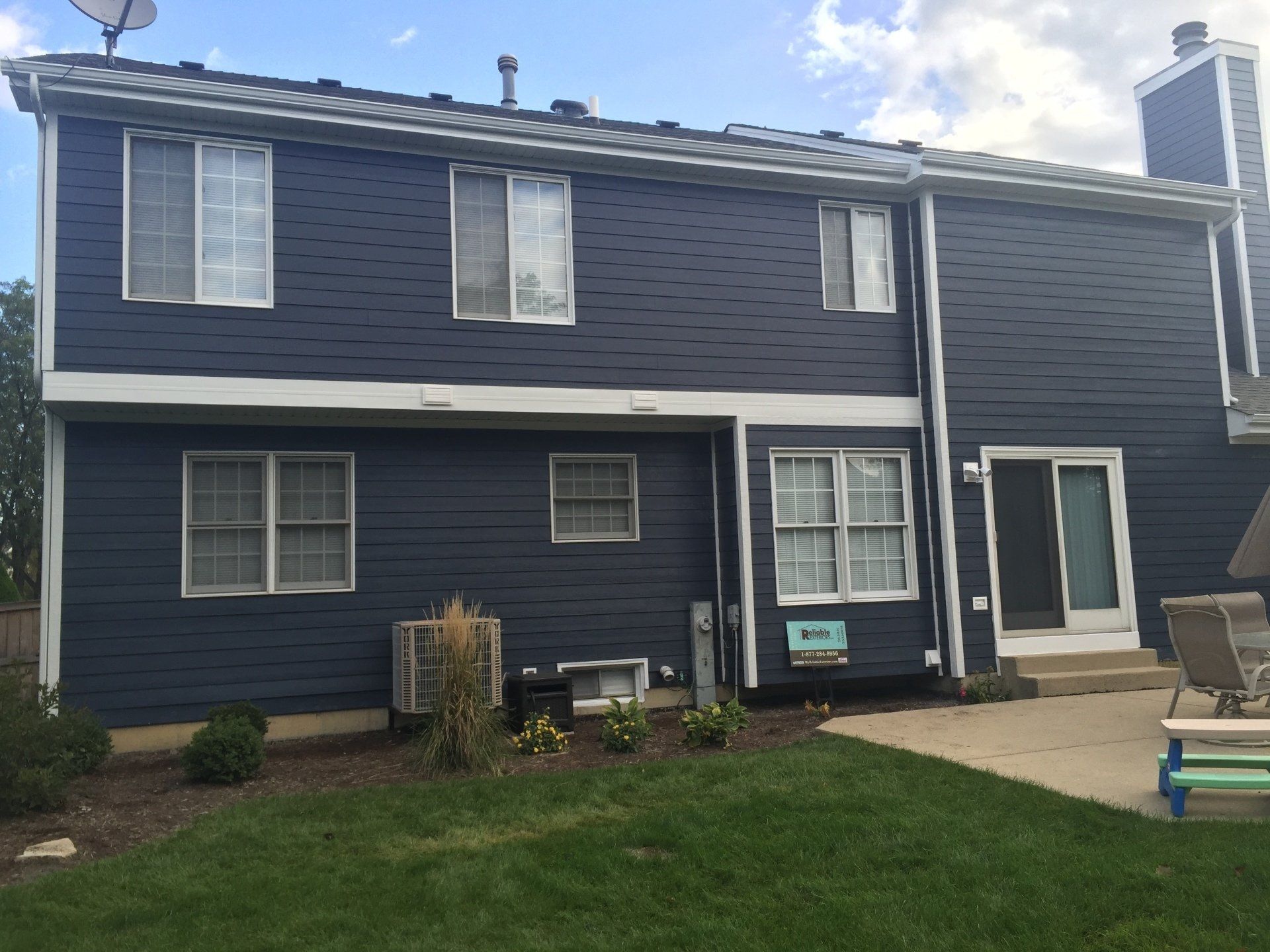 A blue house with a lot of windows and a patio in front of it.