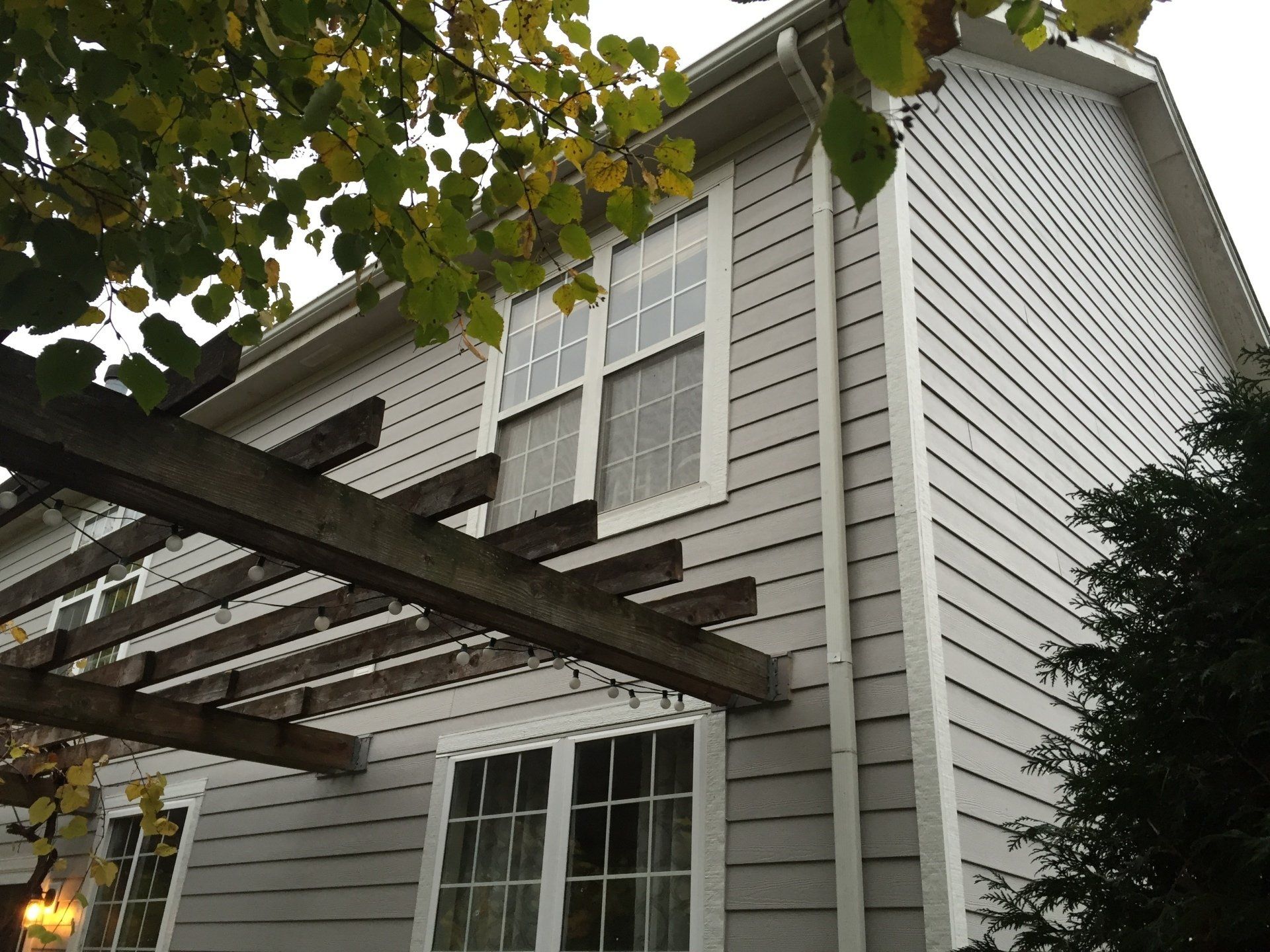 A white house with a pergola on the side of it