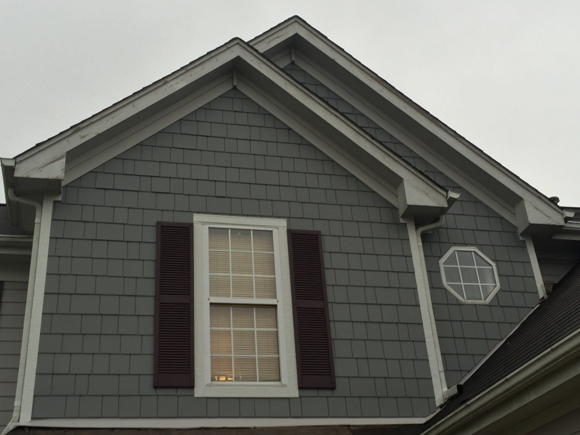 The roof of a house with a window and shutters