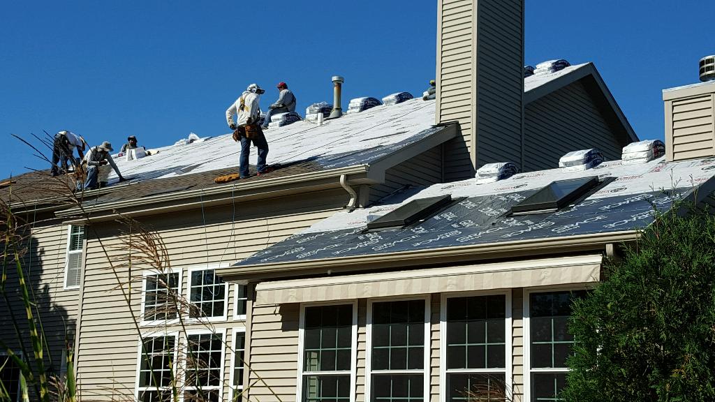A group of men are working on the roof of a house.