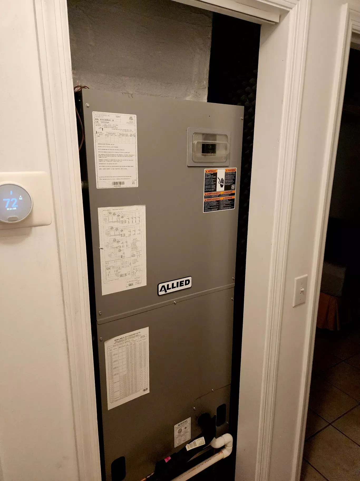 A heater is sitting in a closet next to a door.
