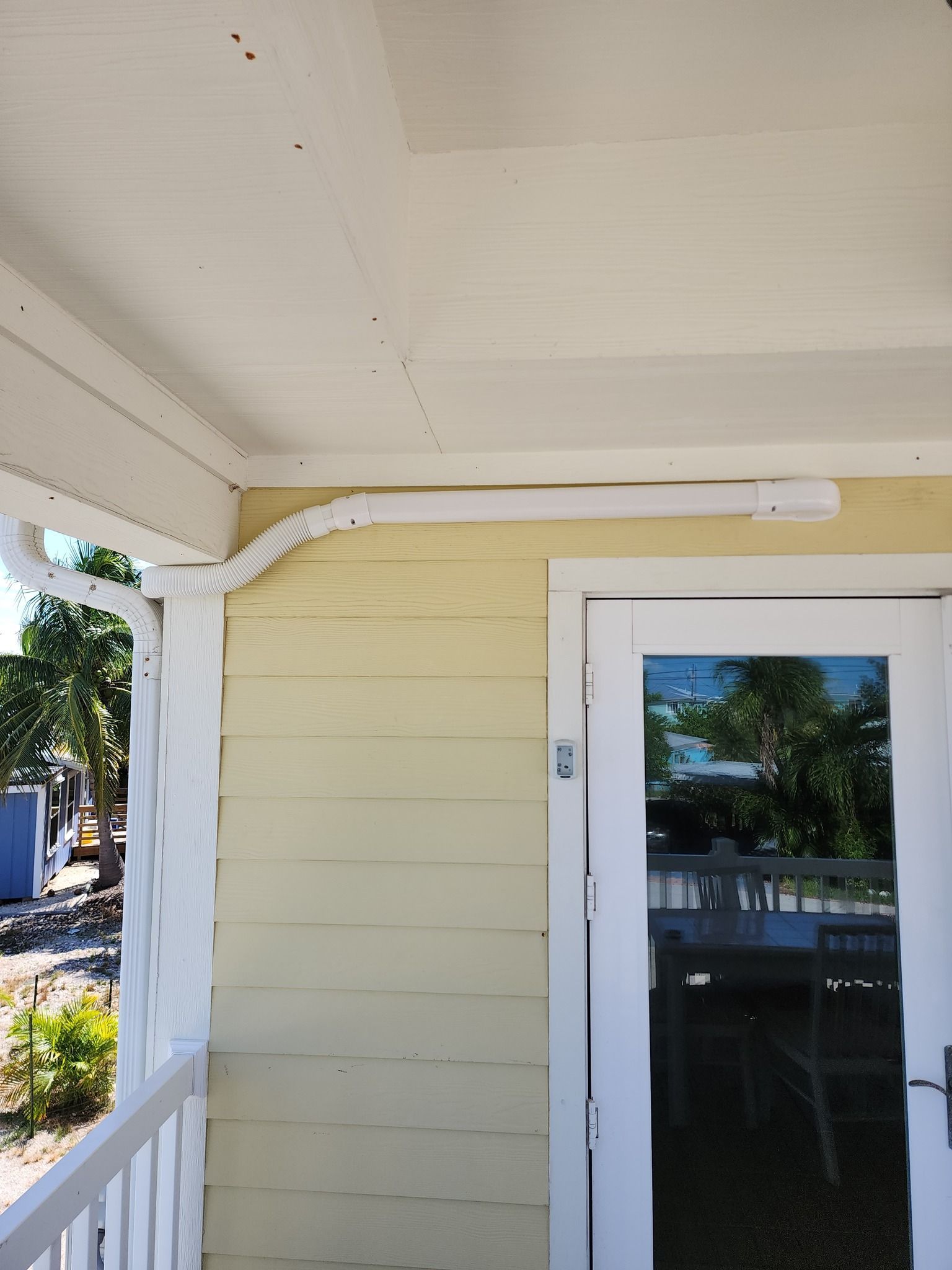 A yellow house with a white door and ac hose
