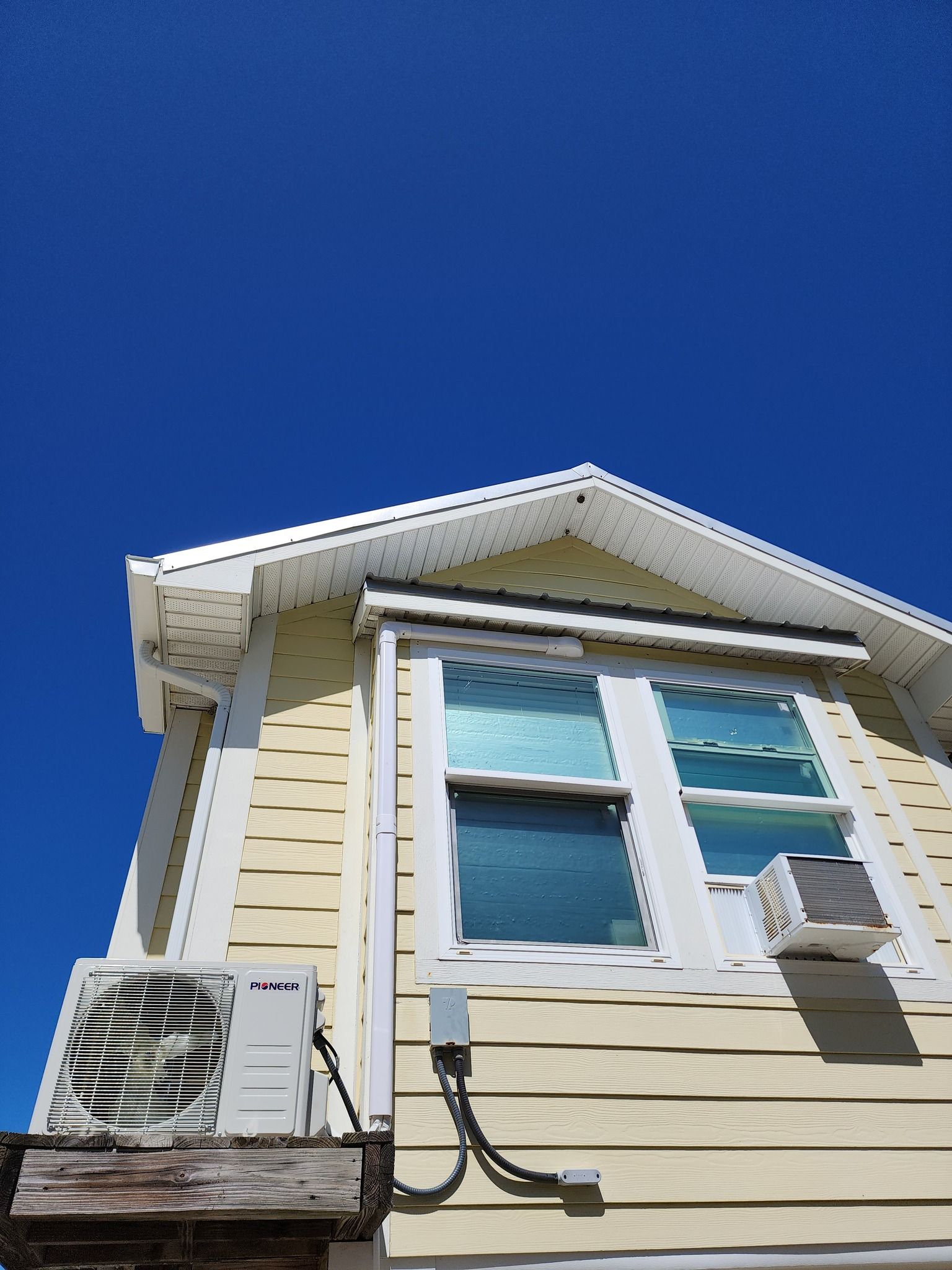 A house with a window and air conditioner on the side of it.