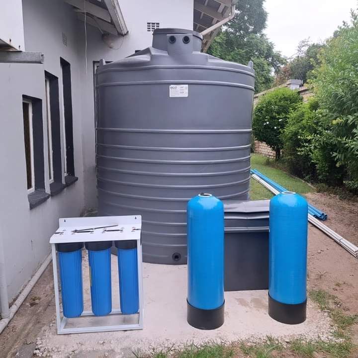 Gray water tank, filters, and other components set up outdoors next to a house.