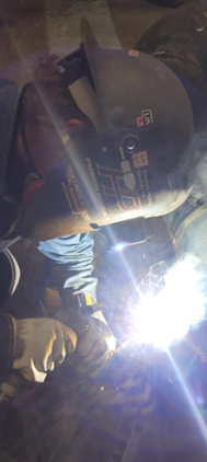 Un homme portant un casque soude un morceau de métal.