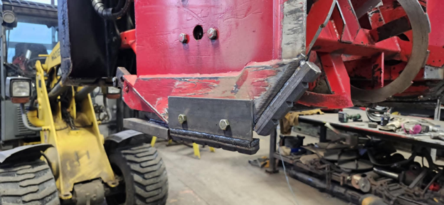 Un chariot élévateur jaune est assis à côté d'une machine rouge dans un garage.