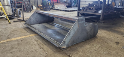 Un grand seau en métal est posé sur le sol dans un garage.