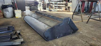 Un seau en métal est posé sur un plancher en bois dans un atelier.