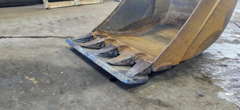 Un godet de bulldozer est posé sur le sol dans un garage.