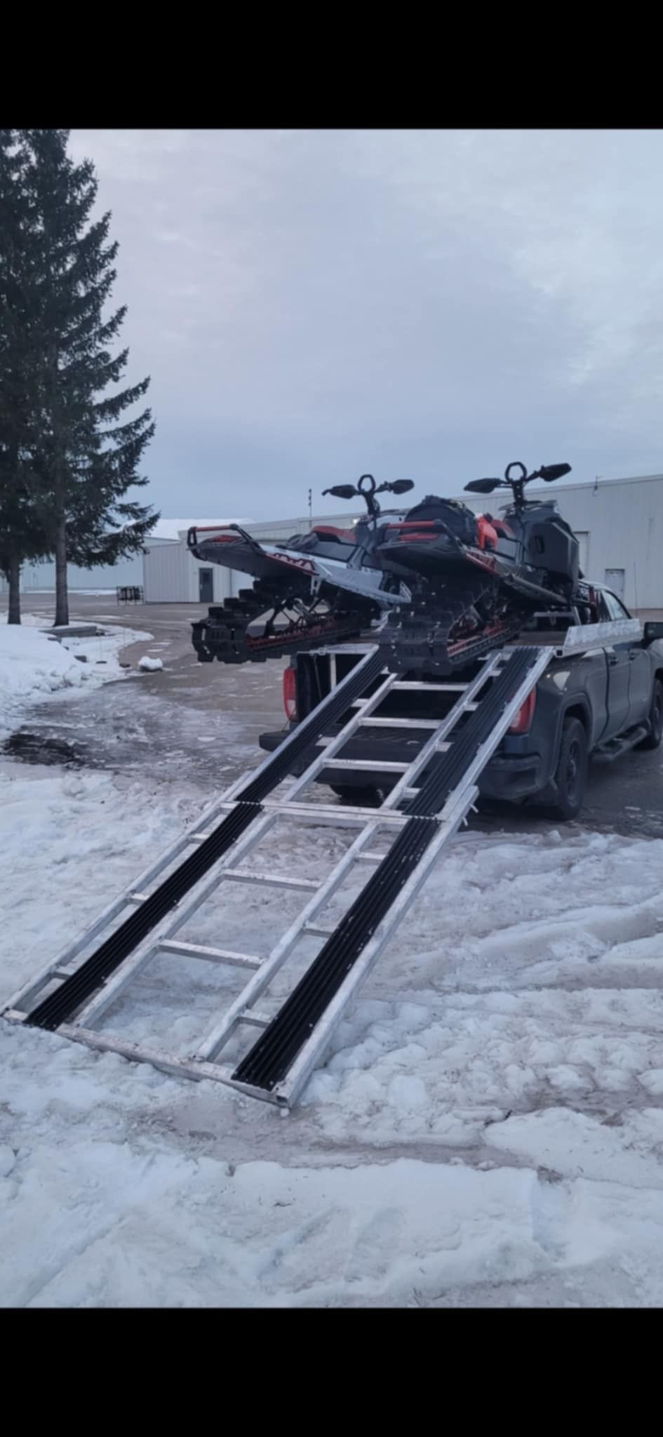 Une motoneige est remorquée sur une rampe dans la neige.
