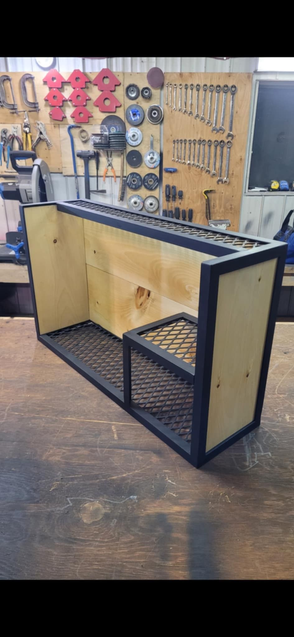 Une table en bois avec un cadre en métal est posée sur un plancher en bois dans un atelier.