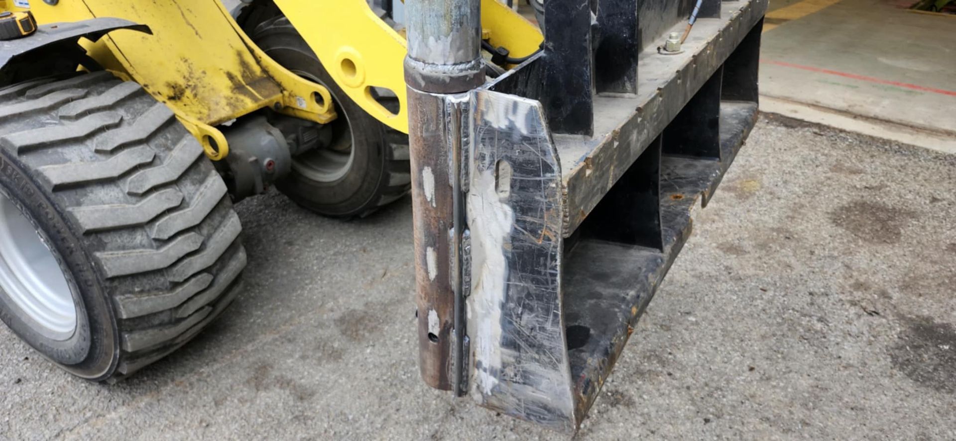 Un tracteur jaune et noir est garé sur le bord de la route.