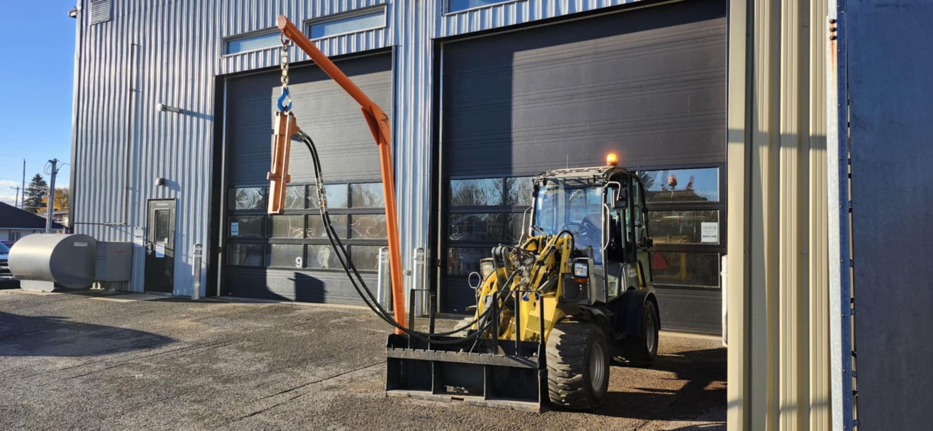Un tracteur jaune est garé devant une porte de garage.