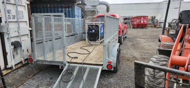 Une remorque est en train d'être chargée avec un générateur sur un parking.