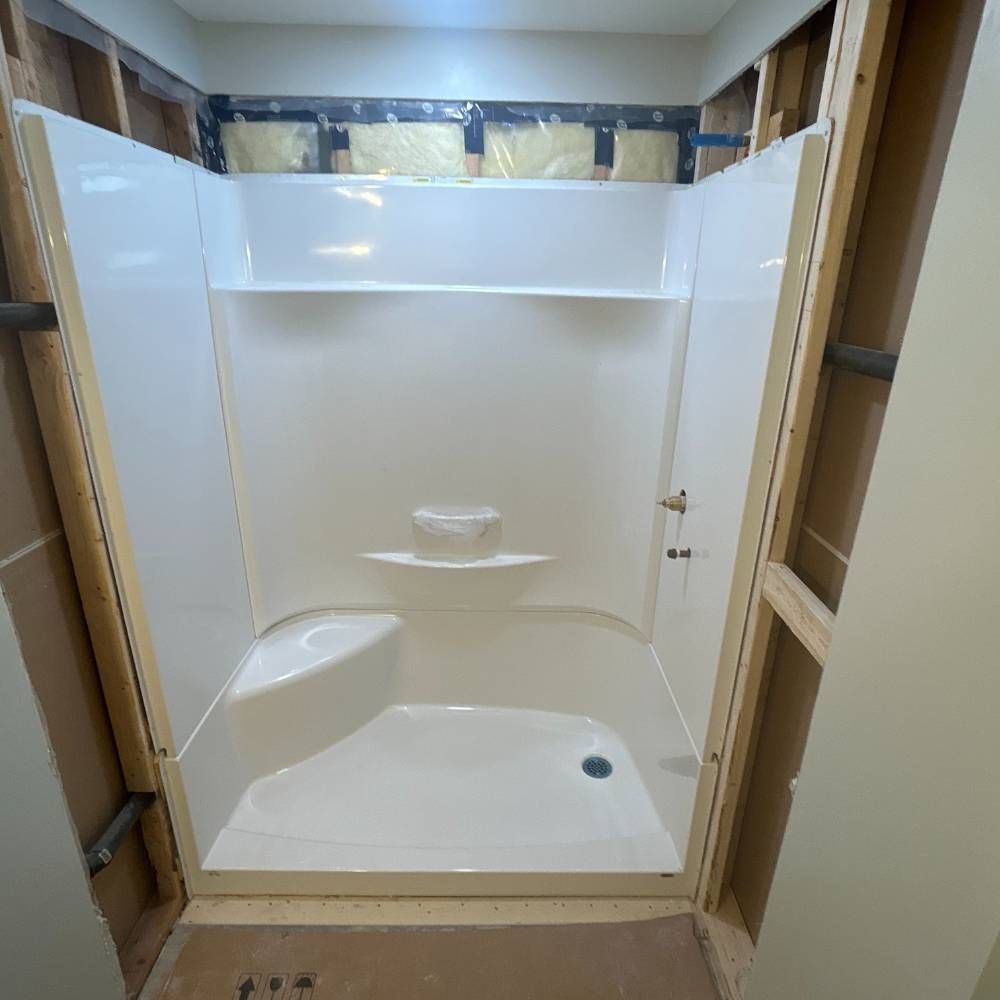 a white shower stall is being built in a bathroom .