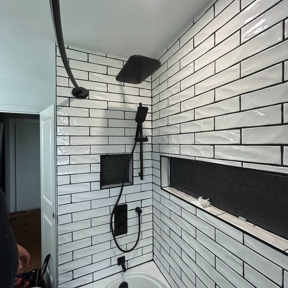 a bathroom with white brick walls and a black shower head