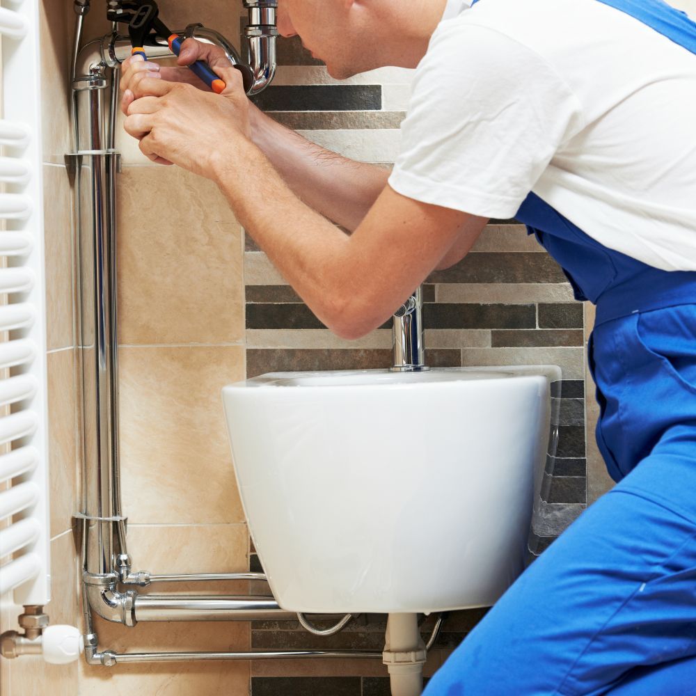 a man in blue overalls is fixing a toilet