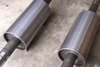 Two metal cylinders are sitting on top of each other on a concrete surface.