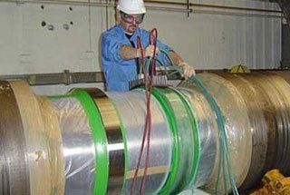 A man is working on a large metal pipe in a factory.