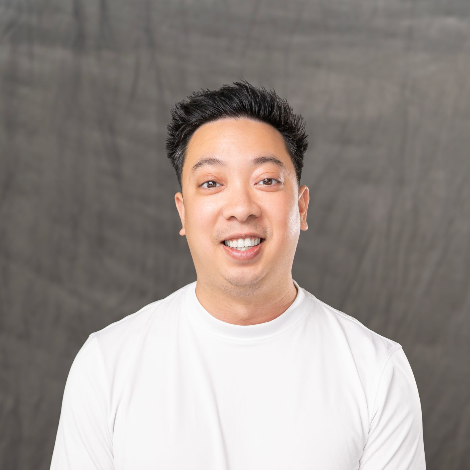 a woman with long hair is wearing a black shirt and standing in front of a white wall .