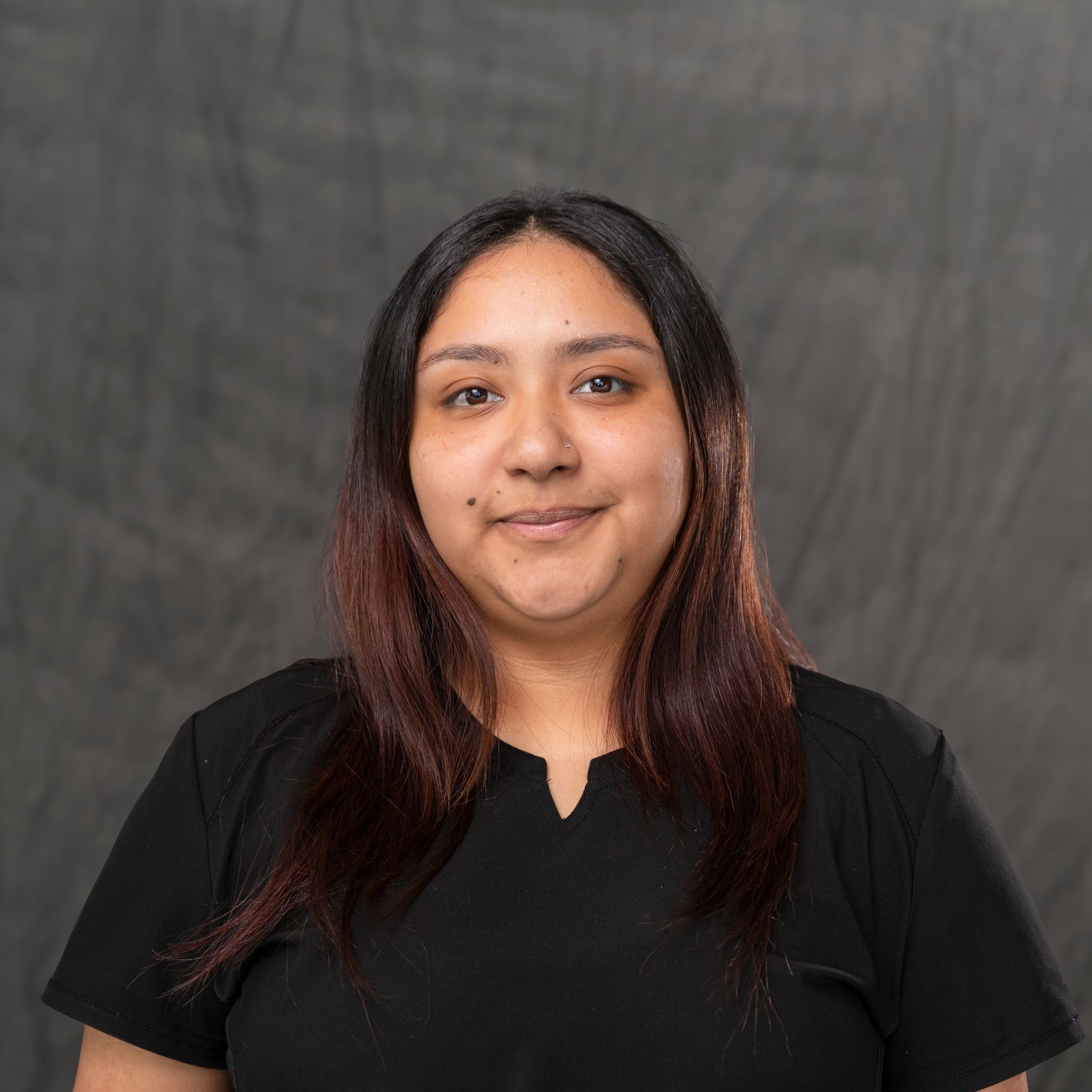 a woman with long blonde hair is wearing a black shirt and a gold necklace .