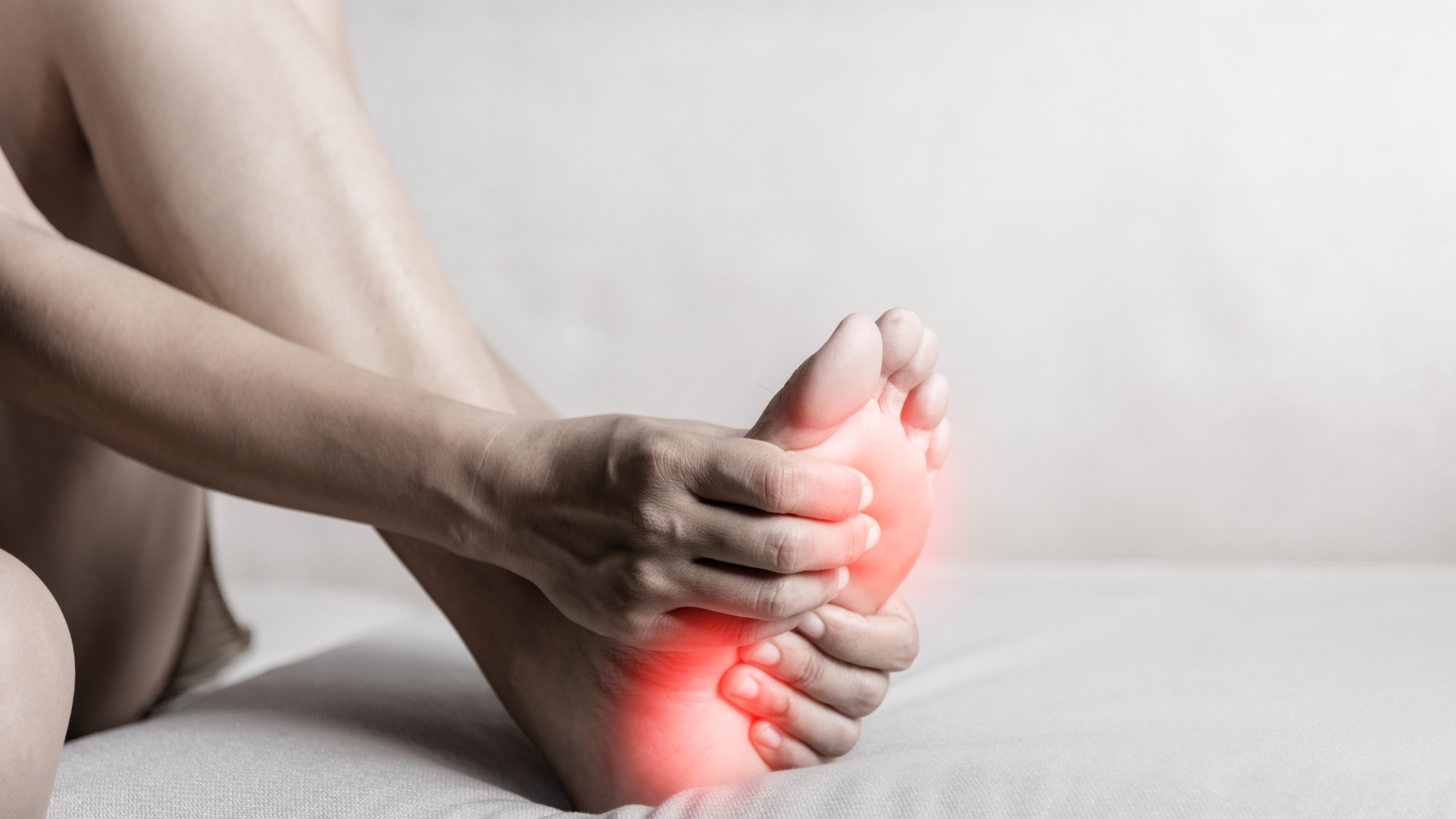 a person is sitting on a bed holding their foot in pain .