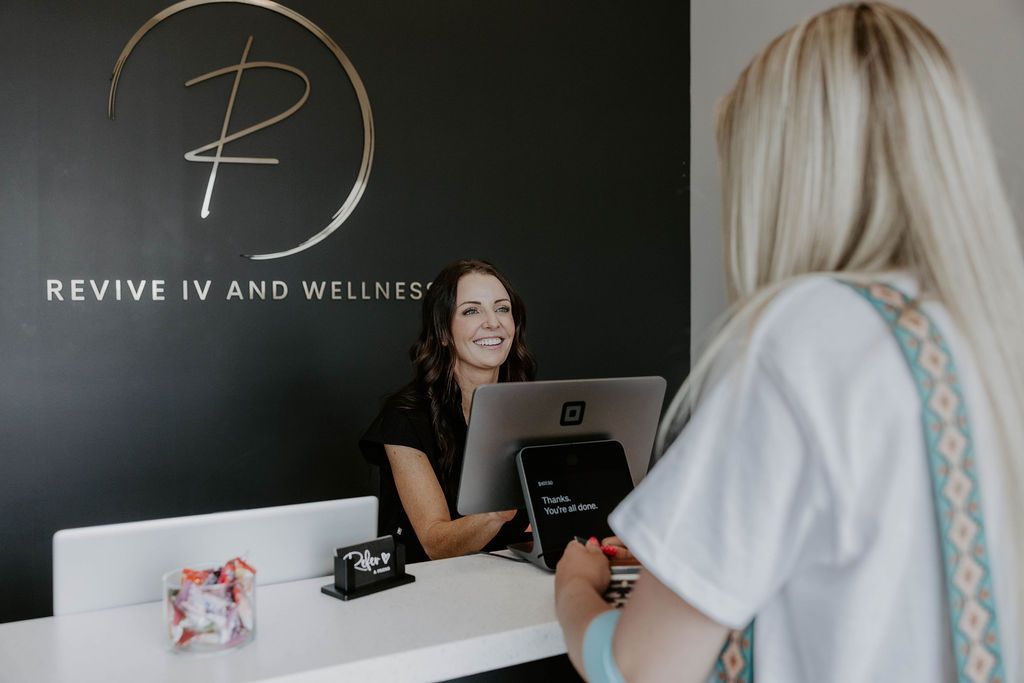 Reception desk at Revive IV and Wellness in Billings MT, with a receptionist helping a client.