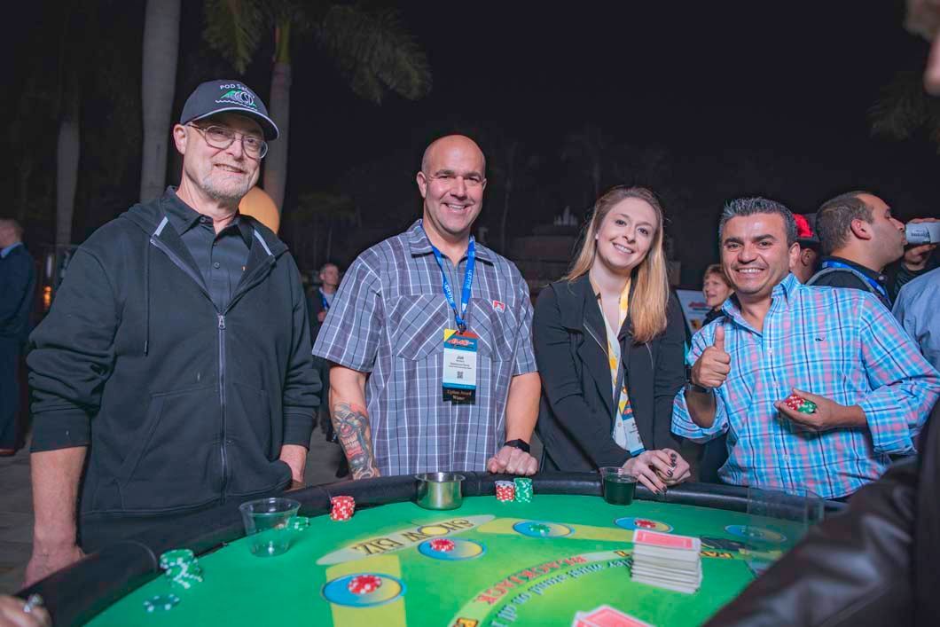 A group of people are standing around a poker table.