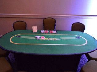 A poker table with cards on it in a room with chairs.