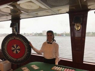A woman is standing in front of a roulette wheel on a boat.