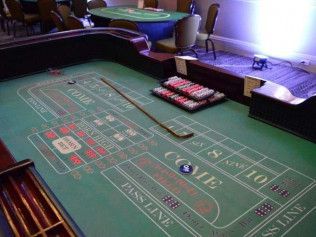 A green roulette table with a wooden stick on it.