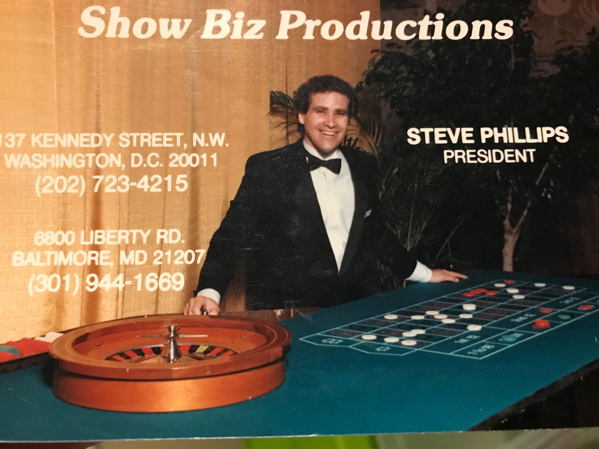 A man in a tuxedo is standing in front of a roulette wheel