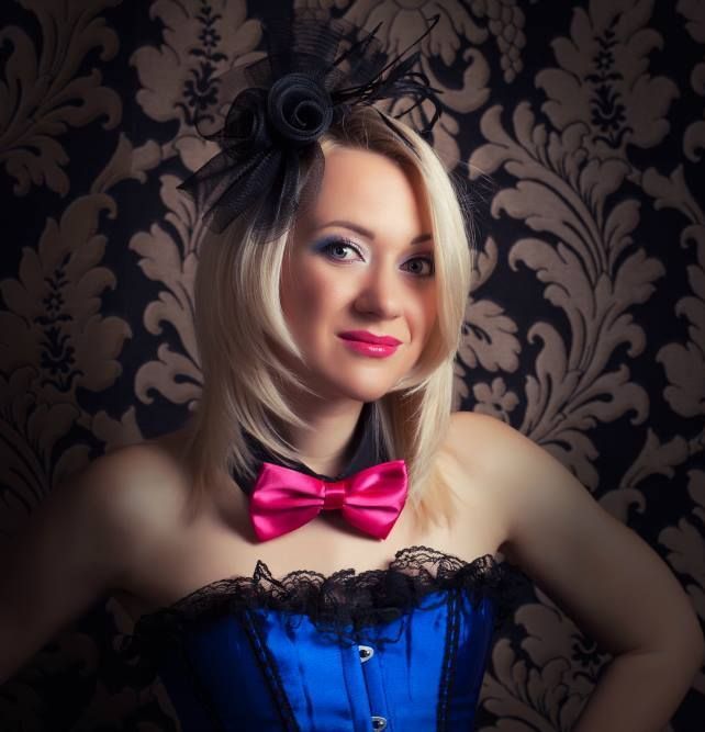 A woman wearing a blue corset and a pink bow tie