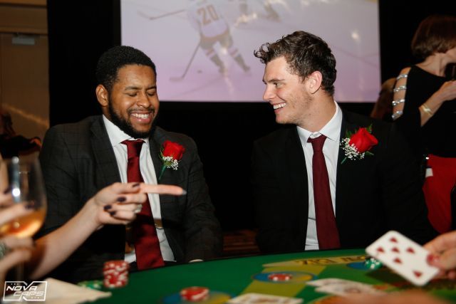 Two men in suits and ties are sitting at a poker table