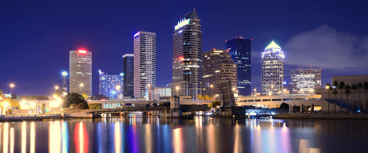 A city skyline is reflected in the water at night.