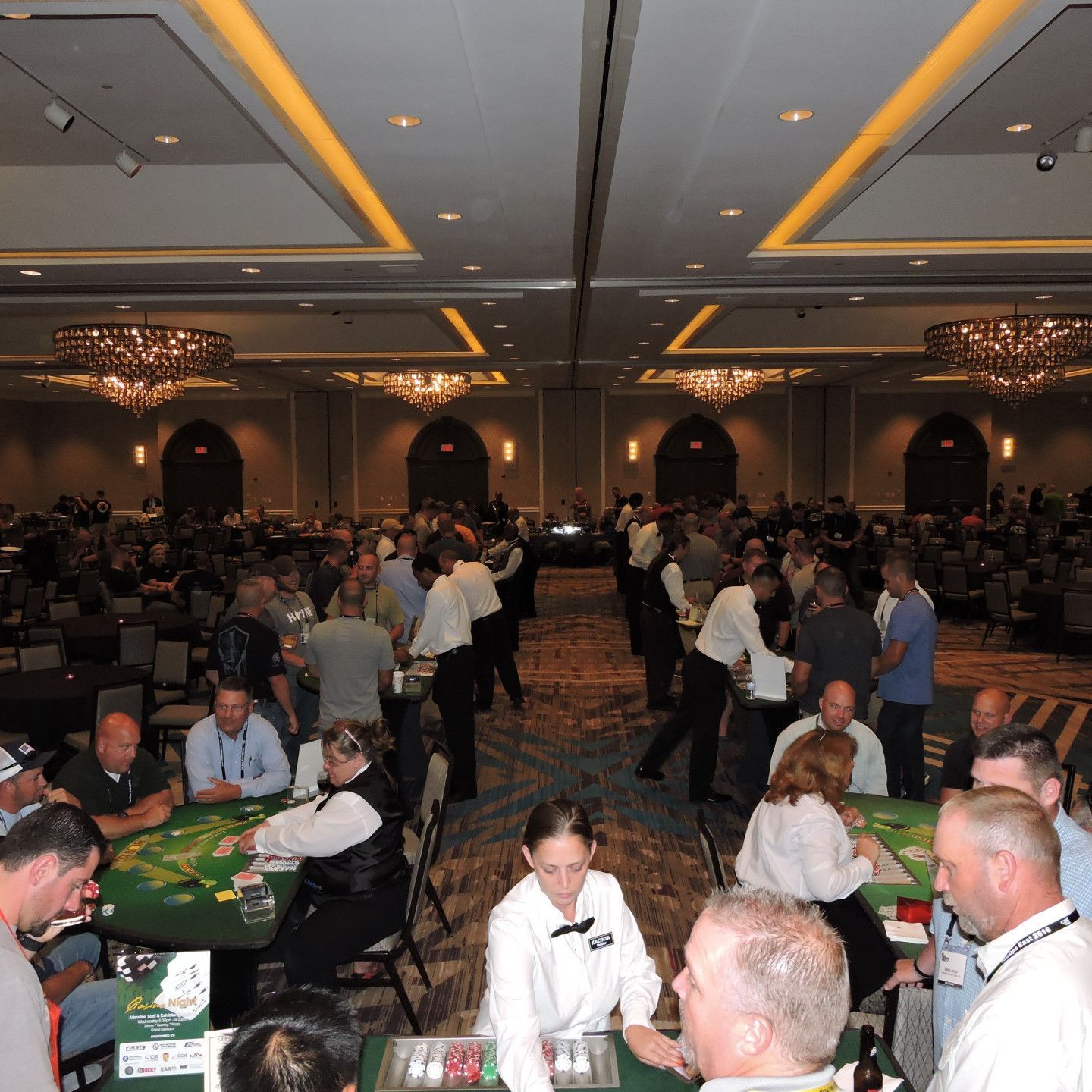 A group of people are playing poker in a large room