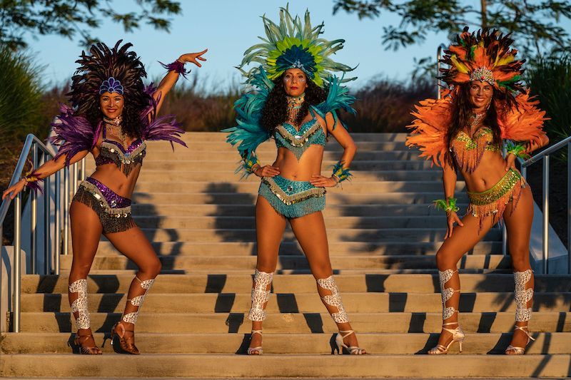 Three women in colorful costumes are standing on a set of stairs