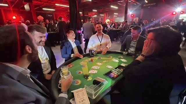 A group of men are sitting around a poker table.