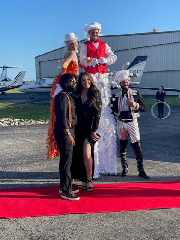 A group of people standing on stilts on a red carpet.