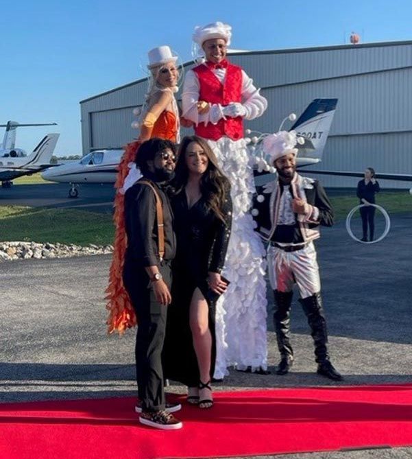 A group of people standing on stilts on a red carpet