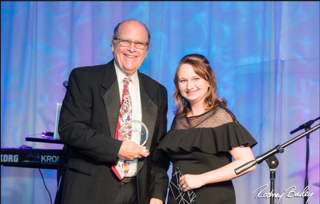 A man and a woman are standing next to each other on a stage.
